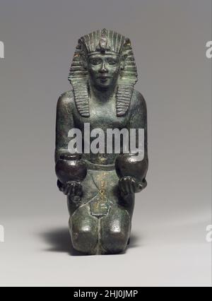 Kneeling statuette of King Amasis 570–526 B.C. Late Period, Saite The childlike appearance of this kneeling statuette, with its large head, beautiful features, plump body, and short legs, is characteristic of some metal royal statues made during the Late Period, when the king was associated with juvenile gods such as Horus, son of Isis. This work, like the stone statuary from the reign of Amasis, testifies to the high level of artistry attained during his rule.The figure is solid-the body, limbs, and attributes were all integrally cast. Precious-metal leaf once covered the king's nemes; additi Stock Photo