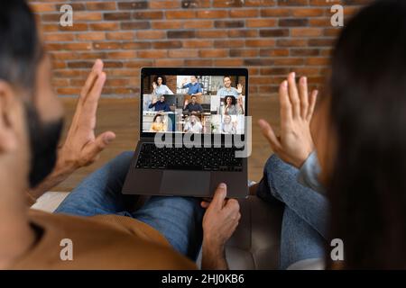 Indian couple using laptop for video connection with friends. Man and woman talking with young people on the screen. Video chatting concept. Stock photo Stock Photo