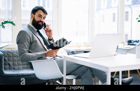Positive bearded entrepreneur talking on phone Stock Photo