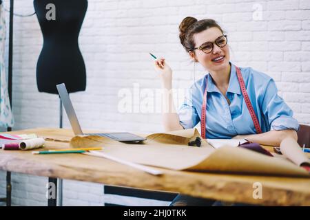 Happy young dressmaker working in sewing studio Stock Photo