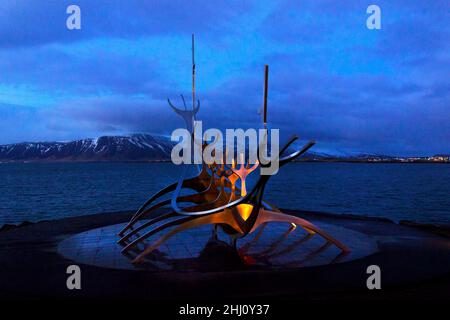 Sun Voyager Viking long=ship steel sculpture  Reykjavik waterfront Iceland Solfarid copy space dream boat evening night time sea & snow capped hills Stock Photo