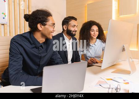 Lively team holding meeting with boss via video link in modern office. Teleconference meeting using computer. Businessman having video call with his business team online, talking about strategy Stock Photo