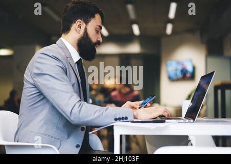 Focused office worker using laptop and smartphone Stock Photo