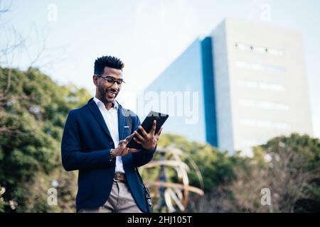 Smiling young black business man using a tablet Stock Photo