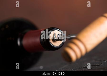 Closeup of Red Wine buttle with corkscrew on dark background Stock Photo