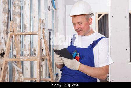 Smiling workman using phone Stock Photo