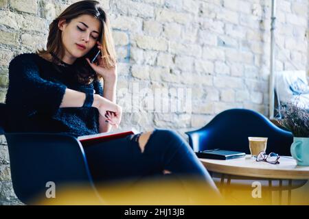 Female freelancer sitting in cafe with smartphone and notebook Stock Photo