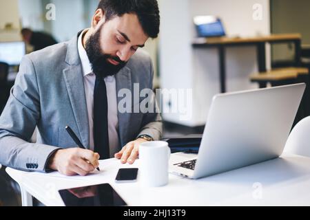 Businessman writing notes while working in office Stock Photo