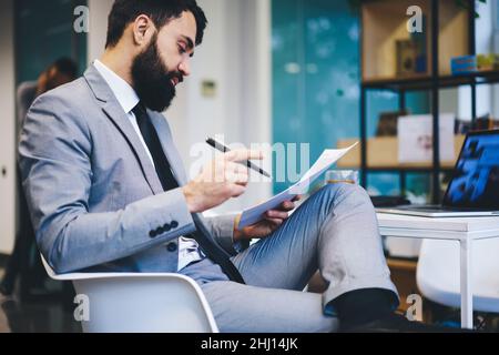Serious entrepreneur reading documents in modern workspace Stock Photo