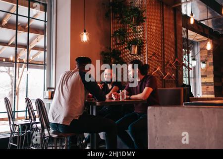 Group of mixed race young men talking in lounge bar. Multiracial friends having fun in cafe drinking coffee. Guys hanging out Stock Photo