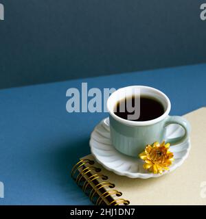 Notebook and cup of coffee on desk. navy blue wall background. workspace Stock Photo