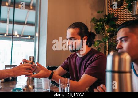 Group of mixed race young men drinking tea in lounge bar. Middle-eastern friends having fun in cafe sharing drinks Stock Photo