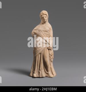 Terracotta statuette of a woman 3rd century B.C. Greek, South Italian, Tarentine Draped, standing head enveloped in himation, right arm akimbo, left at side.. Terracotta statuette of a woman  248608 Stock Photo