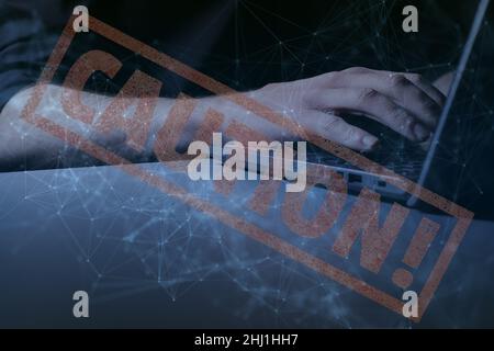 Hands at laptop with interconnectivity graphic overlay along with the word 'CAUTION' displayed large Stock Photo