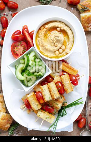 Bowl with delicious hummus, bread and tomatoes on wooden background ...