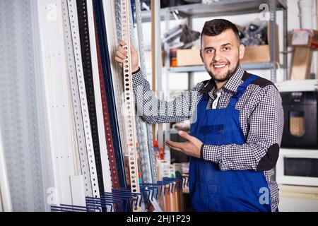 Young man worker examining plastic corners for tiles and floors Stock Photo