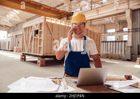 Cheerful male builder talking on cellphone at work Stock Photo