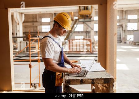 Male builder using modern laptop at work Stock Photo