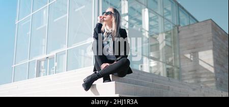 Young businesswoman sitting and thinking outside corporate building Stock Photo