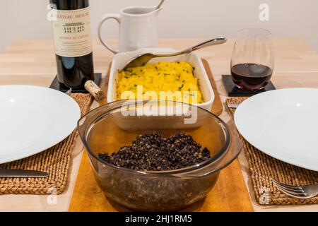 Traditional Scottish Burns Night supper meal: haggis & clapshot (mashed potato & turnip or swede) & bottle of Bordeaux claret Chateau Meaume red wine Stock Photo