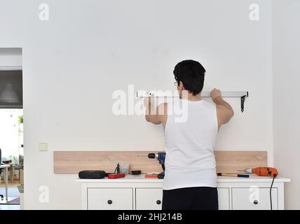 Man measures the spirit level. Wall shelf installation Stock Photo