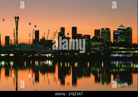 Canary Wharf and the O2 Arena from Royal Victoria Dock, illuminated at sunset, in London Docklands, South East England Stock Photo