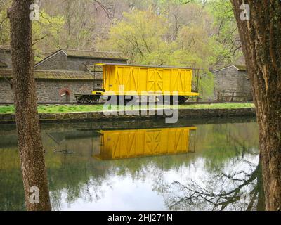 Vintage Train box car yellow on side rail with reflections in a canal. Stock Photo