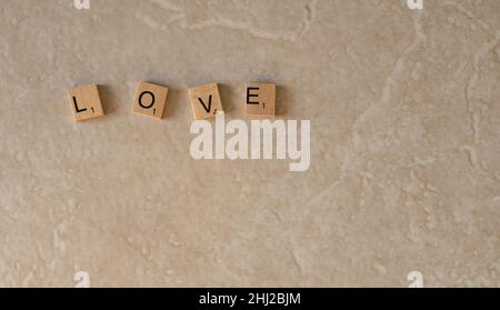 the word love spelt out in wooden squares on a buff background shot from above copy space Stock Photo