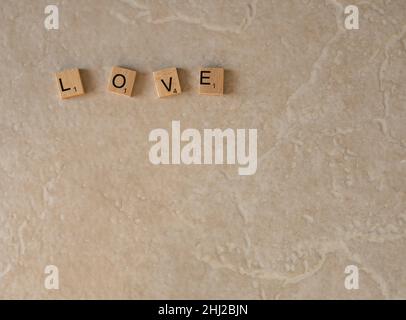 the word love spelt out in wooden squares on a buff background shot from above copy space Stock Photo