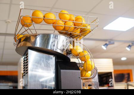 Fresh orange fruits in orange juice machine at store. Juicer in the supermarket. Stock Photo