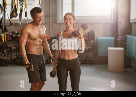 Sporty man in the gym with athletic woman performing sports exercises Stock Photo