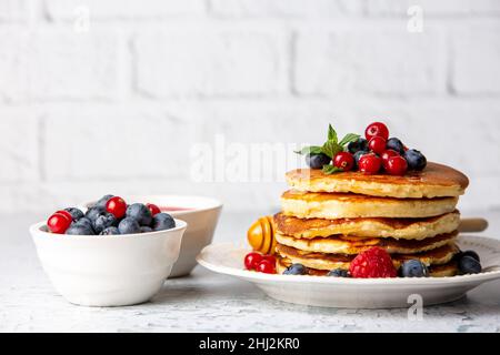 Healthy summer breakfast, homemade classic american pancakes with fresh fruit and honey, morning light gray stone background copy space top view Stock Photo