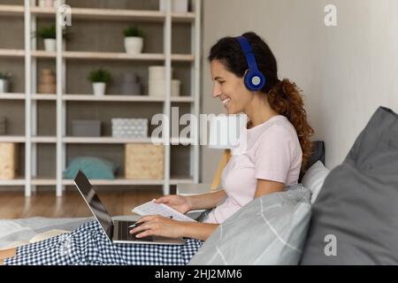Woman looks at laptop listen audio enjoy remote e-learning Stock Photo