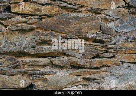 Stone wall texture with clay and spider webs. Old stone wall background. Stock Photo