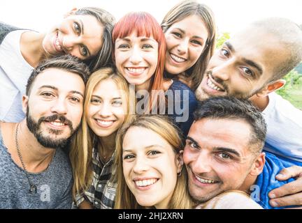 Happy best friends taking selfie outdoors with desaturated backlighting - Youth and friendship concept with young people having fun together Stock Photo