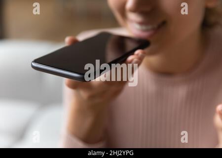 Close up female hand holds smartphone near mouth using speakerphone Stock Photo