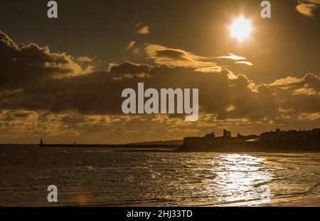 Crepuscular rays shine down on Tynemouth, the Priory & the pier in the northeast of England on a cloudy day Stock Photo