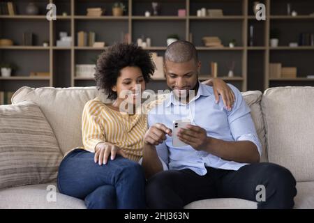 African couple in love relaxing on couch with mobile phone Stock Photo