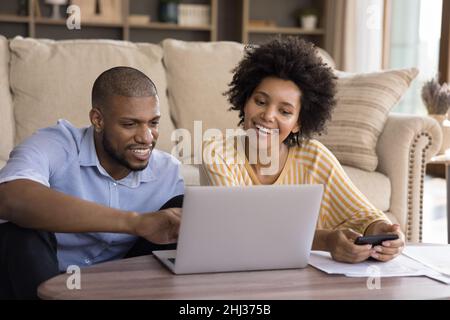 Smiling African couple calculate their earnings and expenses at home Stock Photo