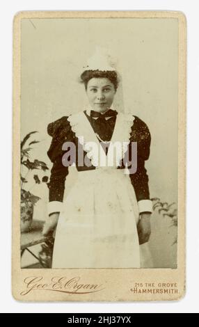 Original Victorian era Carted de Visite (CDV or visiting card) of pretty young Victorian maid, Victorian servants, wearing a lace cap and apron, puffed sleeves, Victorian maid's uniform, studio Geo (George) E. Organ, 215 The Grove, Hammersmith,  London, U.K. circa.1898 Stock Photo