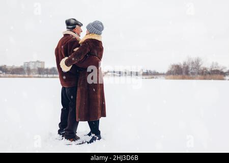 Senior family couple dancing outdoors during snowy winter weather. Elderly people having fun walking. Valentine's day Stock Photo