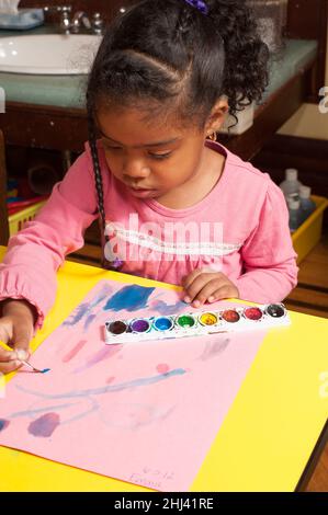 Education Preschool 3-4 year olds art activity girl painting with water colors Stock Photo