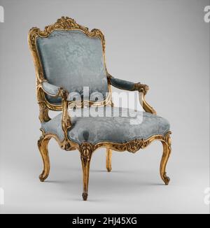 Armchair (fauteuil à la reine) ca. 1750–60 Southwestern German The flowing, curvilinear silhouette of this exuberantly carved armchair is close in inspiration to a design attributed to the French ornamentist and court goldsmith Juste-Aurèle Meissonier (1695–1750), who was named architect and designer to the king in 1726. Meissonier's chair is characterized by the same overall sweep of the back and cabochon-cartouches heading the legs, and a similar disposition of the armrests. As in the Museum's example, the crest and front rail are centered by an ornamental carving that retains a certain symm Stock Photo