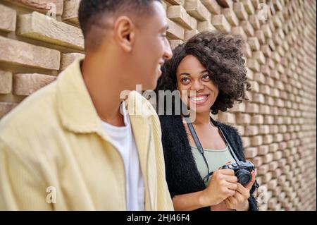 Dark-skinned woman looking at man near brick wall Stock Photo
