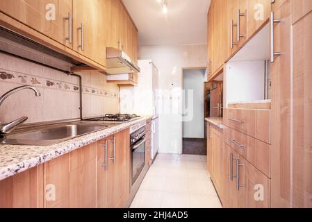 Kitchen with lots of light wood cabinets, pink granite countertops and cream tile in short term rental apartment Stock Photo