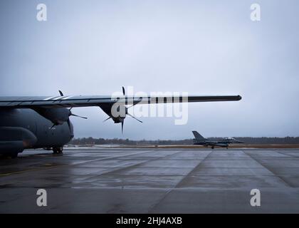 A Belgian F-16 taxis past a C-130J Super Hercules, assigned to the 86th Airlift Wing from Ramstein Air Base, Germany, at Ämari Air Base, Estonia Jan. 24, 2022.    The C-130J and F-16 are providing support to a NATO enhanced air policing mission. Enhanced air policing demonstrates NATO’s solidarity, collective resolve and its ability to adapt and scale its defensive missions and deterrence posture in response to the evolving security situation facing the alliance. (U.S. Air Force Photo by Staff Sgt. Megan Beatty) Stock Photo