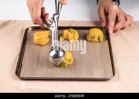 Scooping cookie dough with dough scoop into a baking sheet lined with  parchment paper to bake soft oatmeal raisin walnut cookies Stock Photo -  Alamy