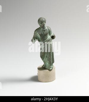 Bronze statuette of a man ca. 1st–2nd century A.D. Roman Weight on left leg; right arm extended with hand open; left lowered and bent at elbow; wearing a tunic and mantle.. Bronze statuette of a man  244459 Stock Photo