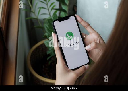 CHIANG MAI, THAILAND - JAN 15, 2022: Woman holding iPhone 12 with social networking service WhatsApp on the screen. iPhone was created and developed Stock Photo