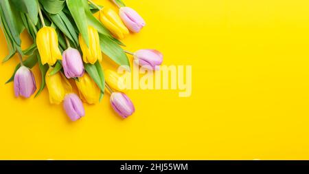Spring floral background with multicolored tulips on yellow background. Top view. Copy space Stock Photo